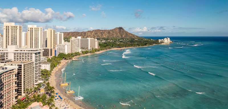 Crystal clear turquoise waters of a Maui beach with lush green mountains in the background